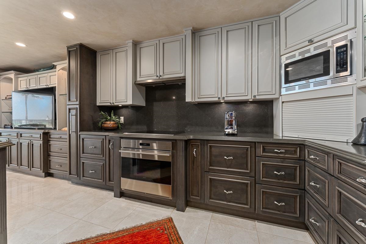 Kitchen with dark wood cabinets, light gray upper cabinets, and stainless steel appliances.