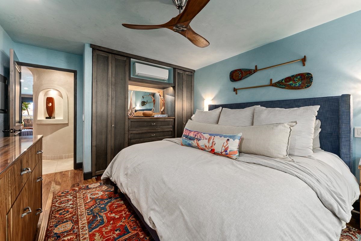 Bedroom with a white bed, blue headboard, turquoise walls, and dark wood built-in cabinets.