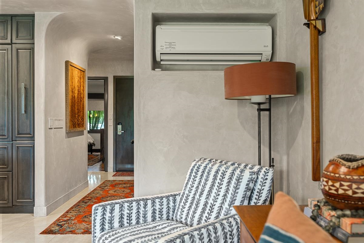 Furnished living area with a patterned armchair, colorful rug, and hallway to a bedroom.