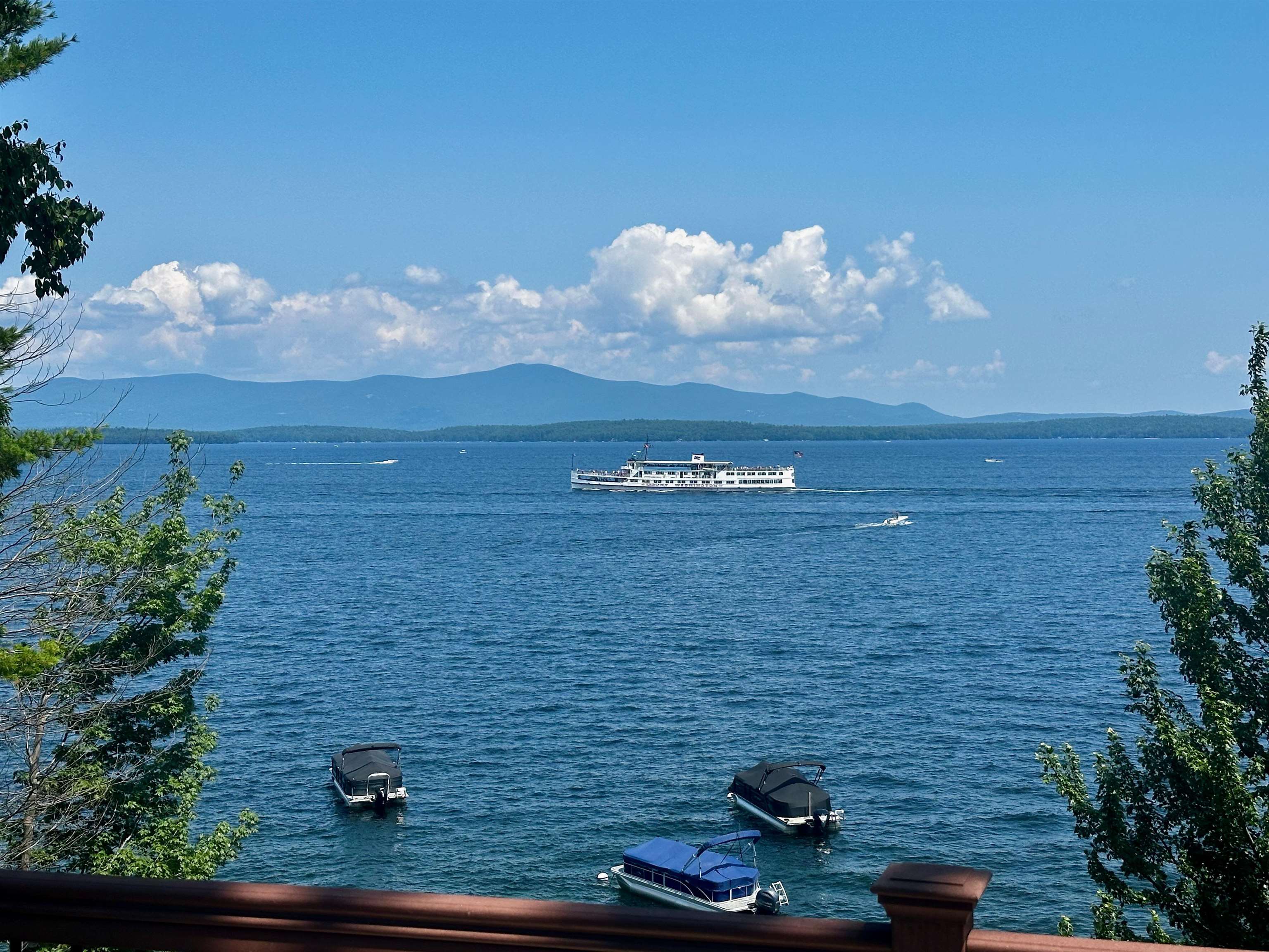 Lake view with a cruise boat crossing the water and mountains on the horizon.