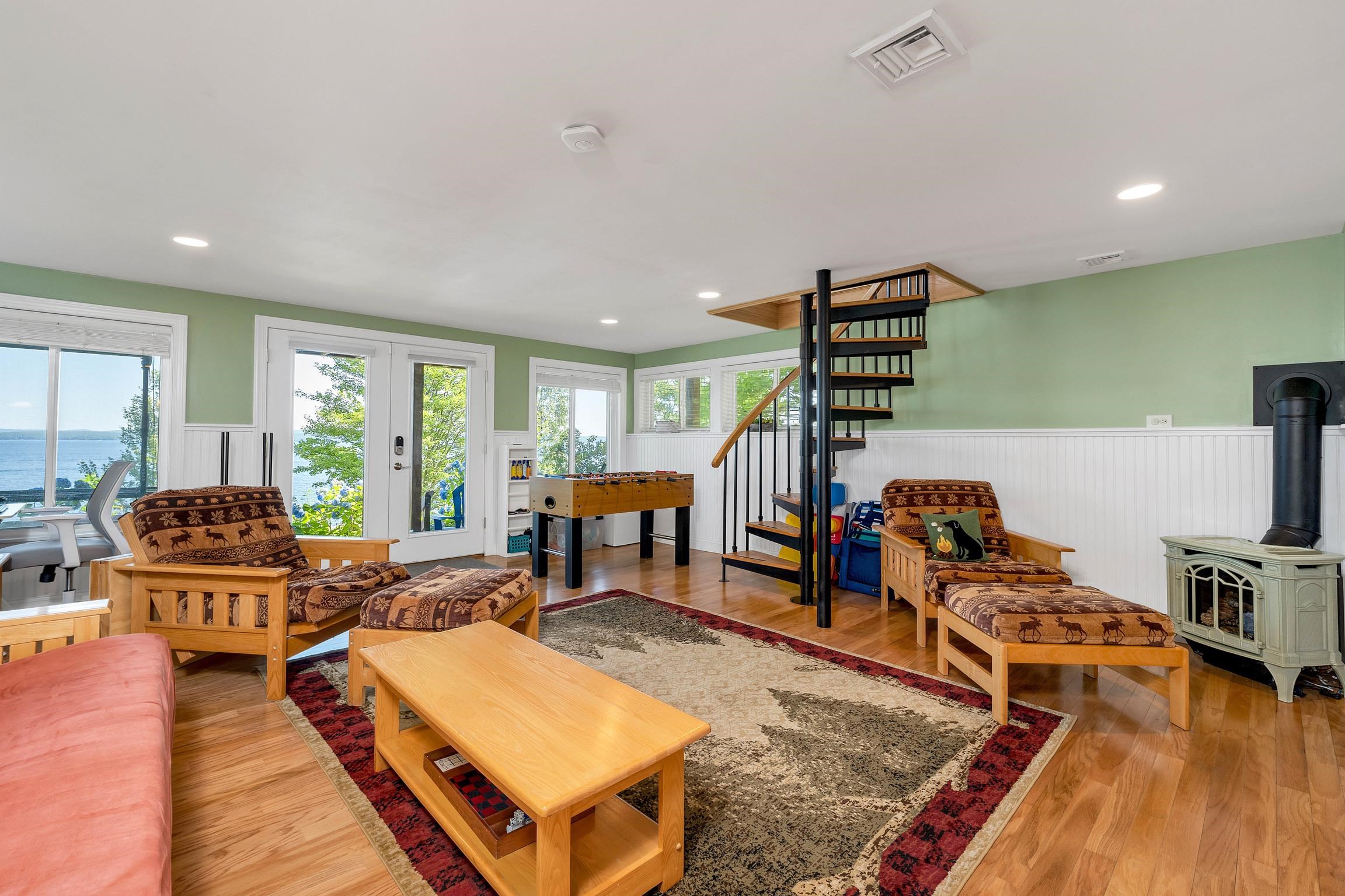 Furnished recreation room with a foosball table, spiral staircase, wood stove, and lake views.