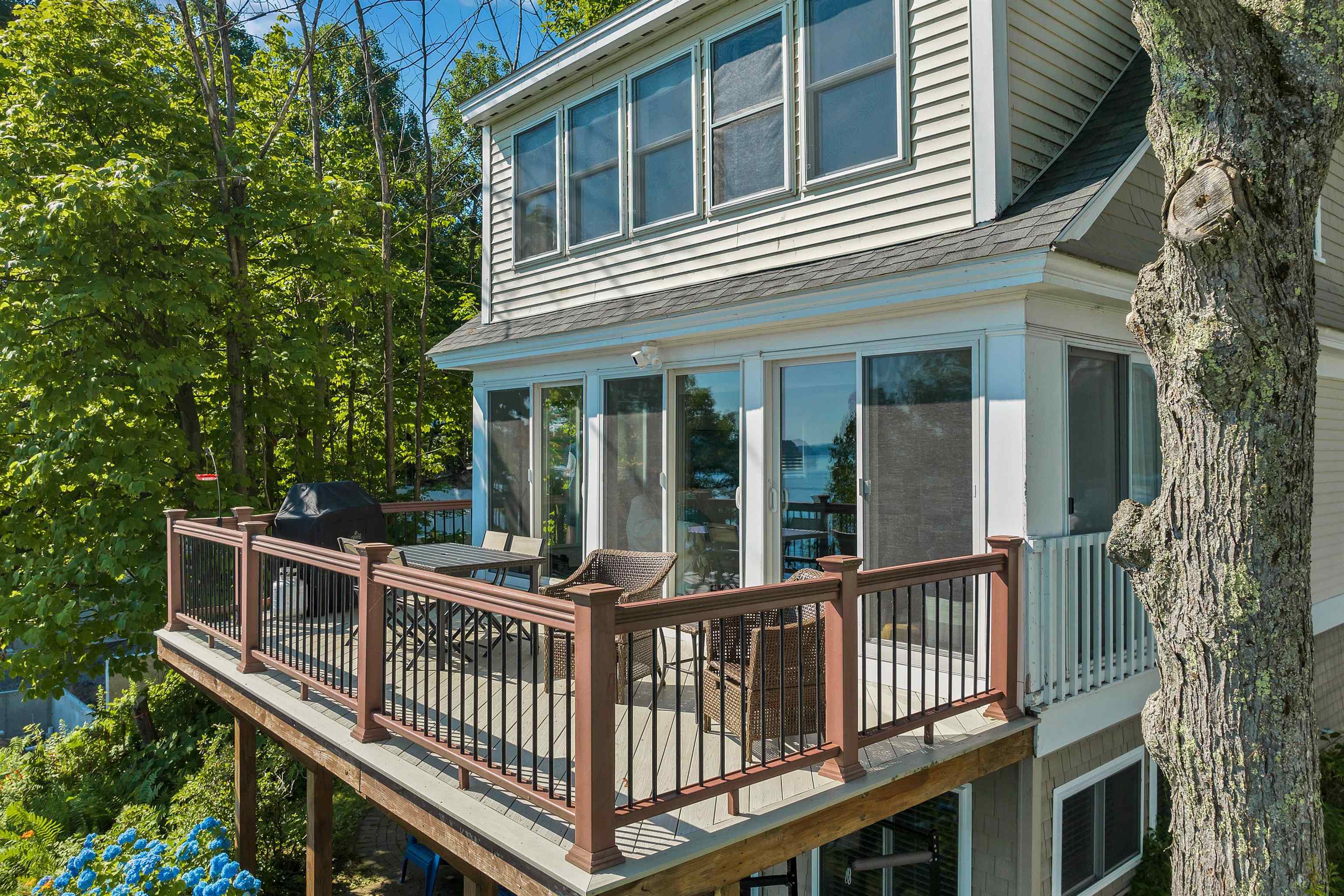 Lakeside home with a furnished raised deck and water visible through the glass doors.