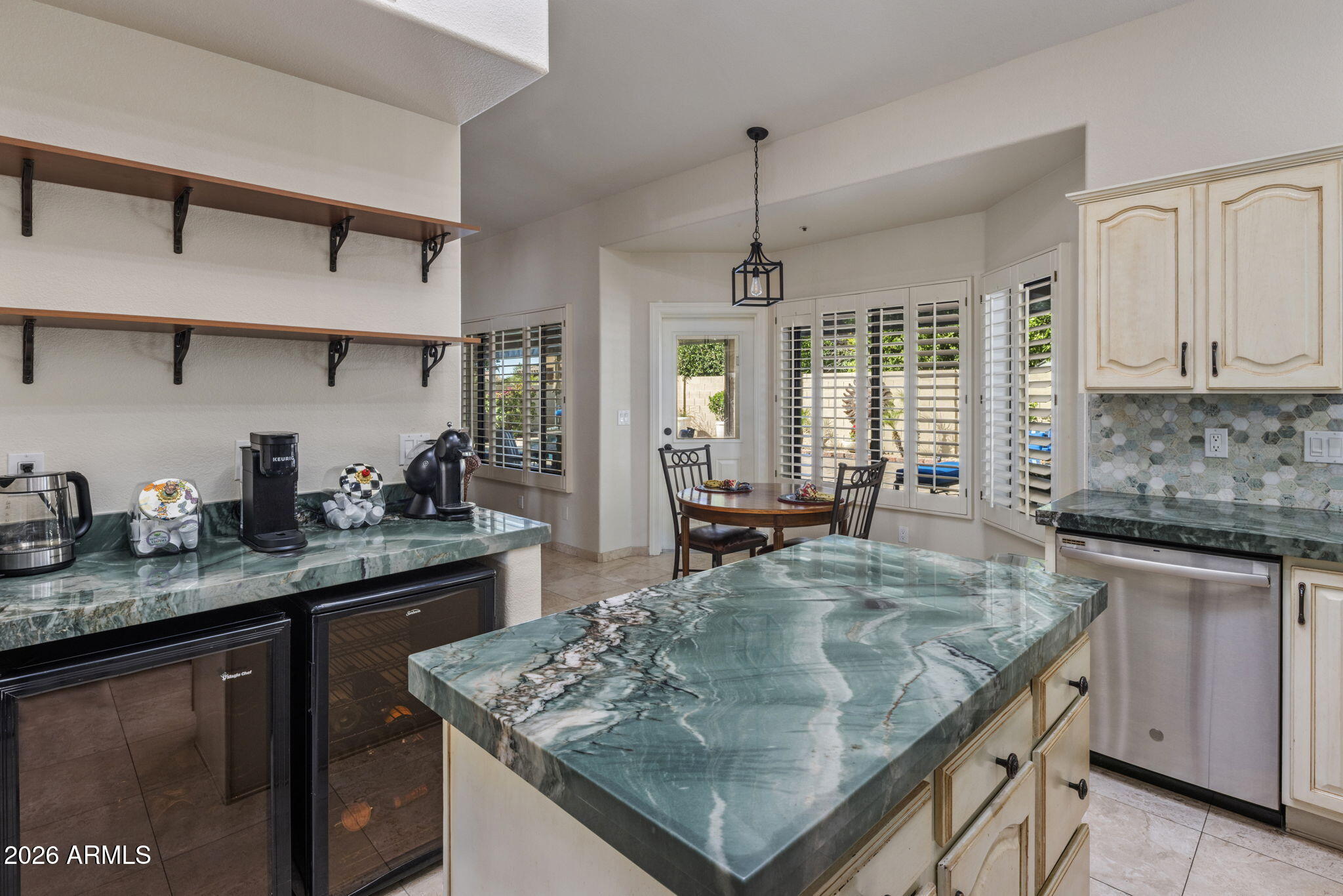 Kitchen with a dramatic veined stone island and a dining nook by shuttered windows.