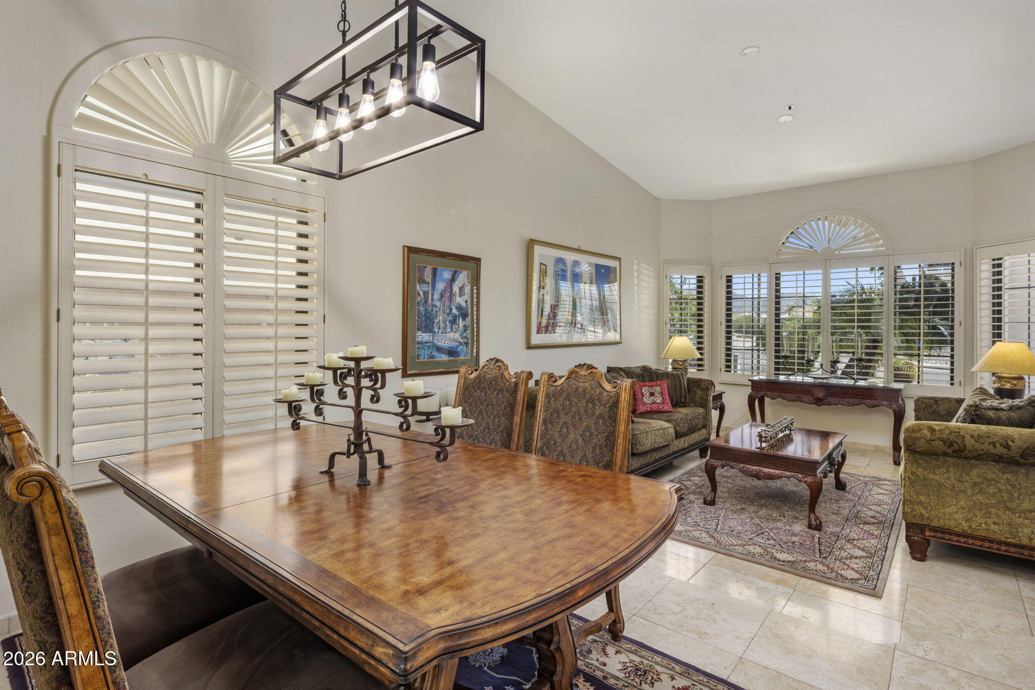 Furnished living and dining room with plantation shutters and a large wooden table.
