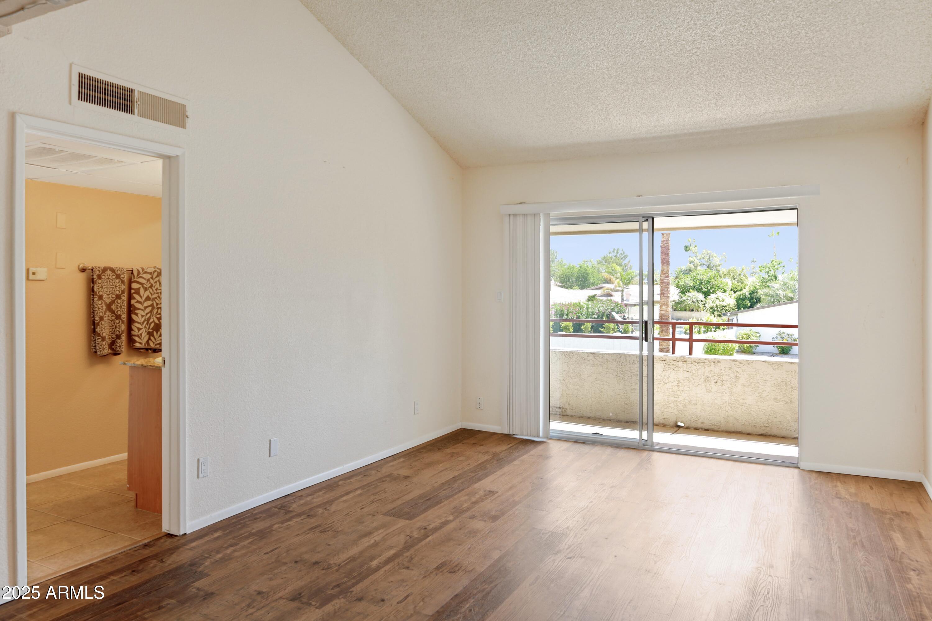 Empty living area with wood-look flooring and sliding glass doors to a balcony.