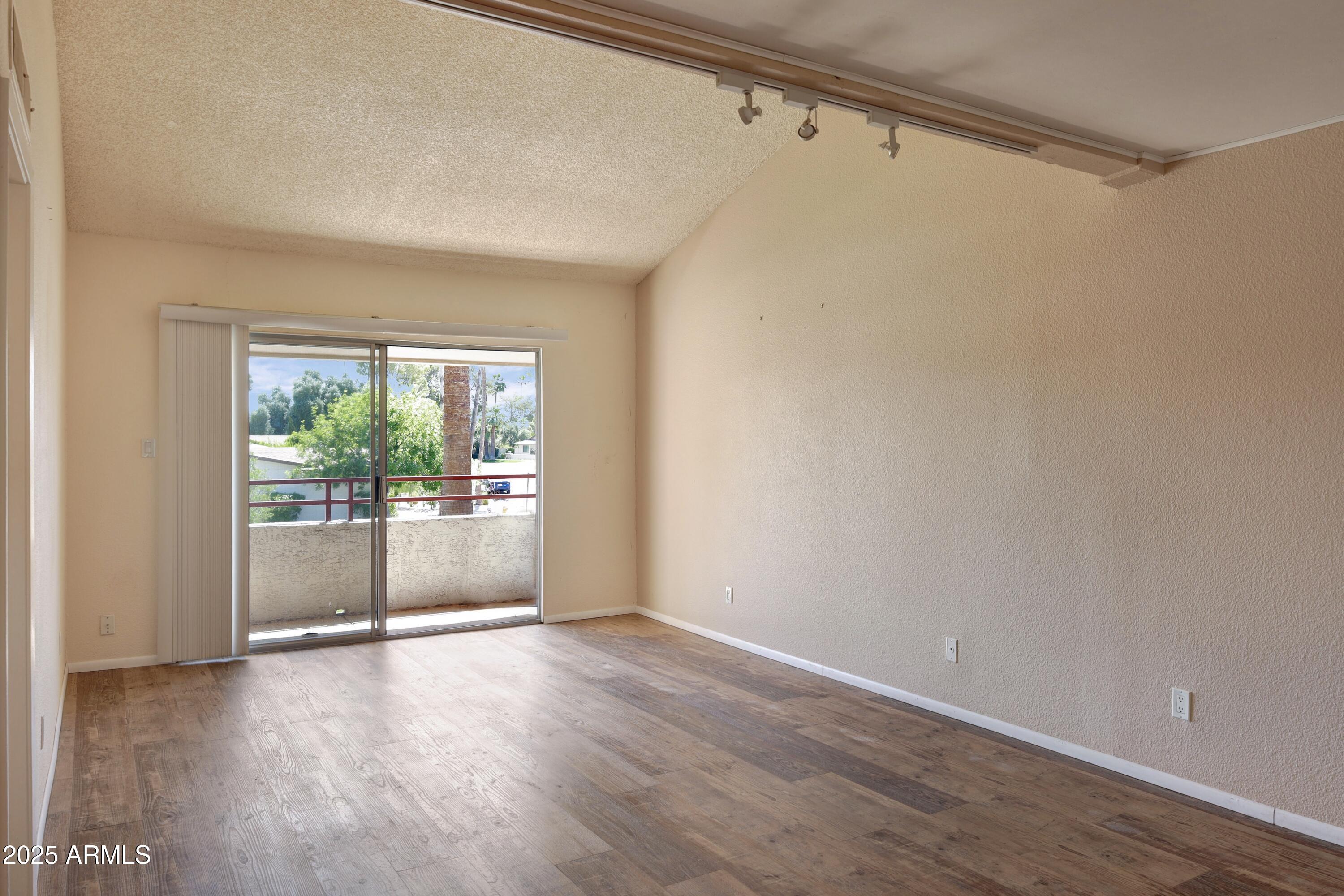 Vacant living room with wood-look floors and a sliding glass door to a balcony.