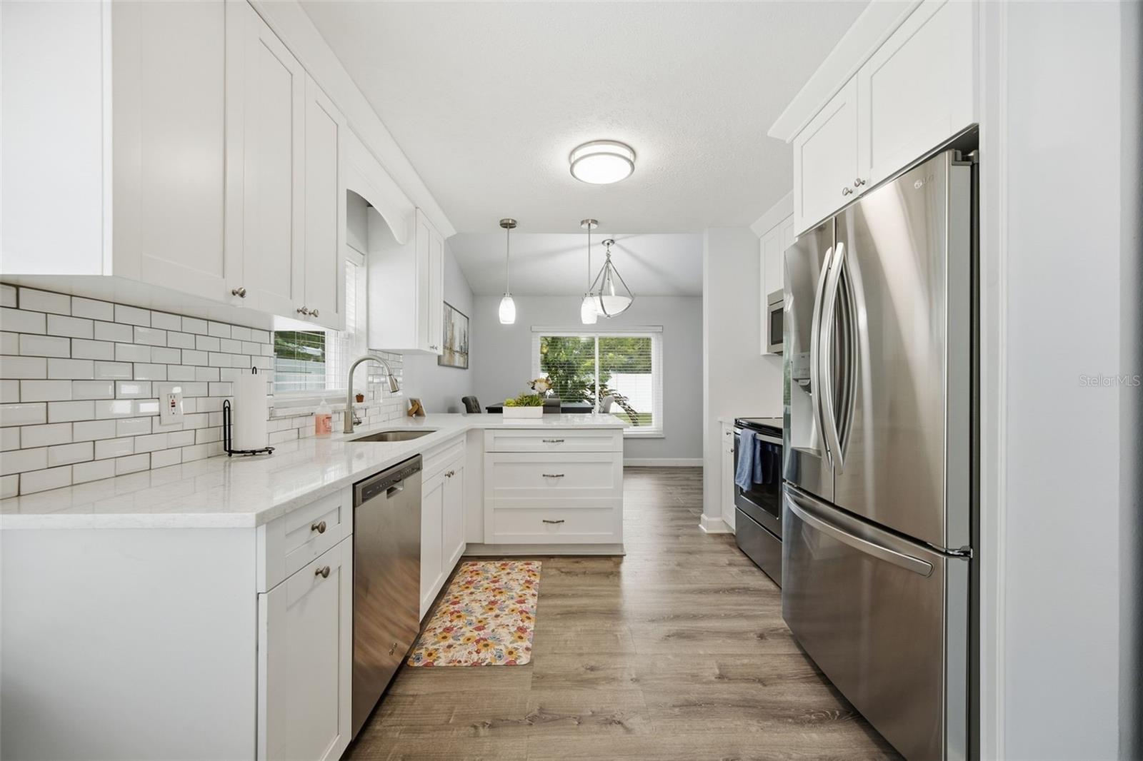 Bright white kitchen with subway tile backsplash, stainless steel appliances, and a small central island.