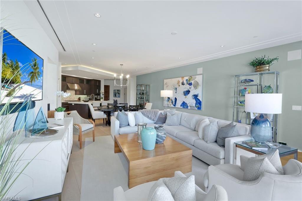 Furnished living room with a gray sectional, wood coffee table, and open kitchen.