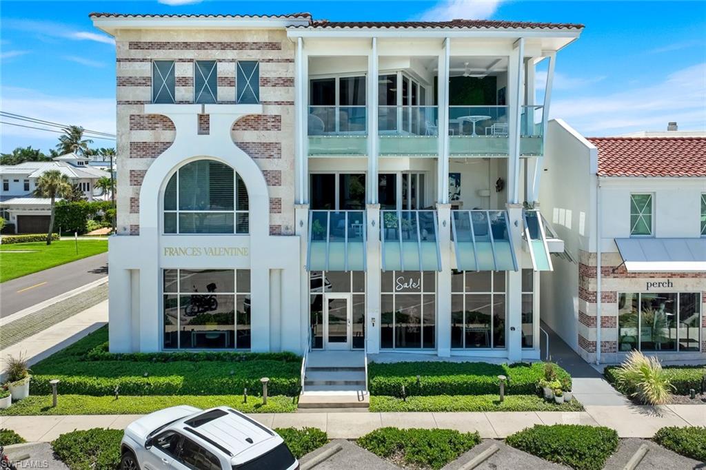Modern building with glass balconies, a brick-and-white facade, and landscaped frontage.