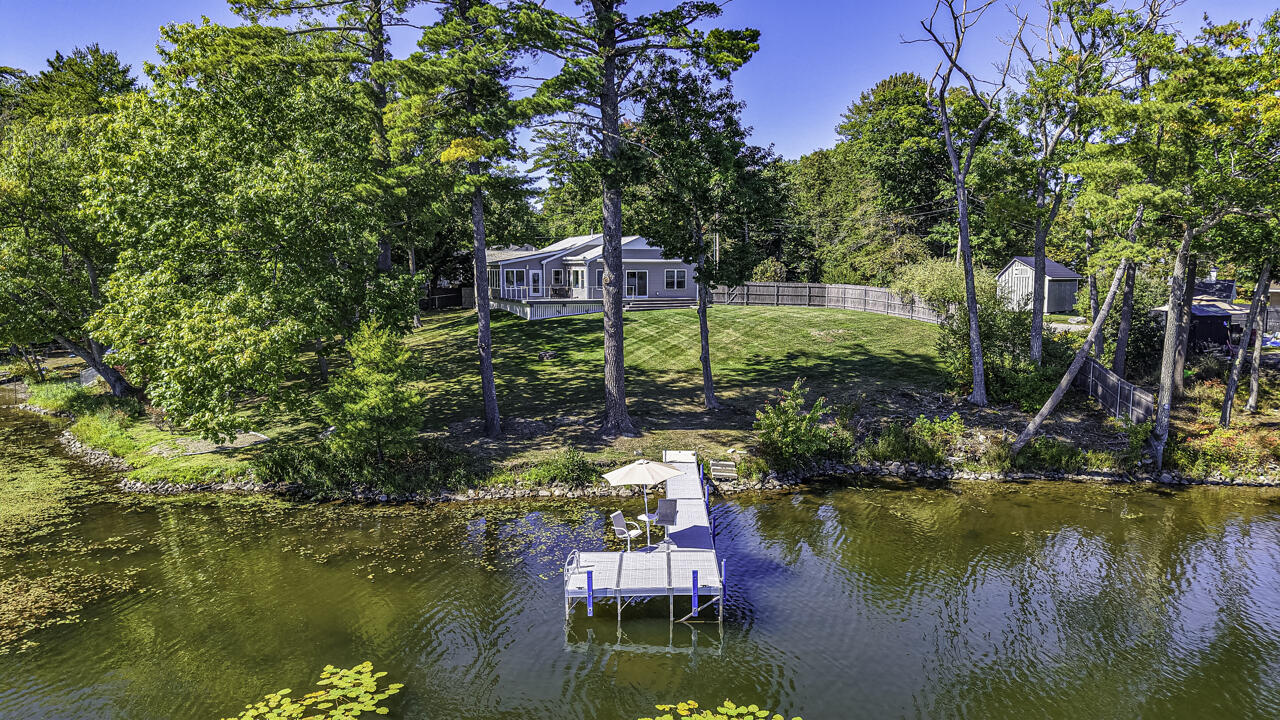 Waterfront home with a large lawn and dock extending into the water.