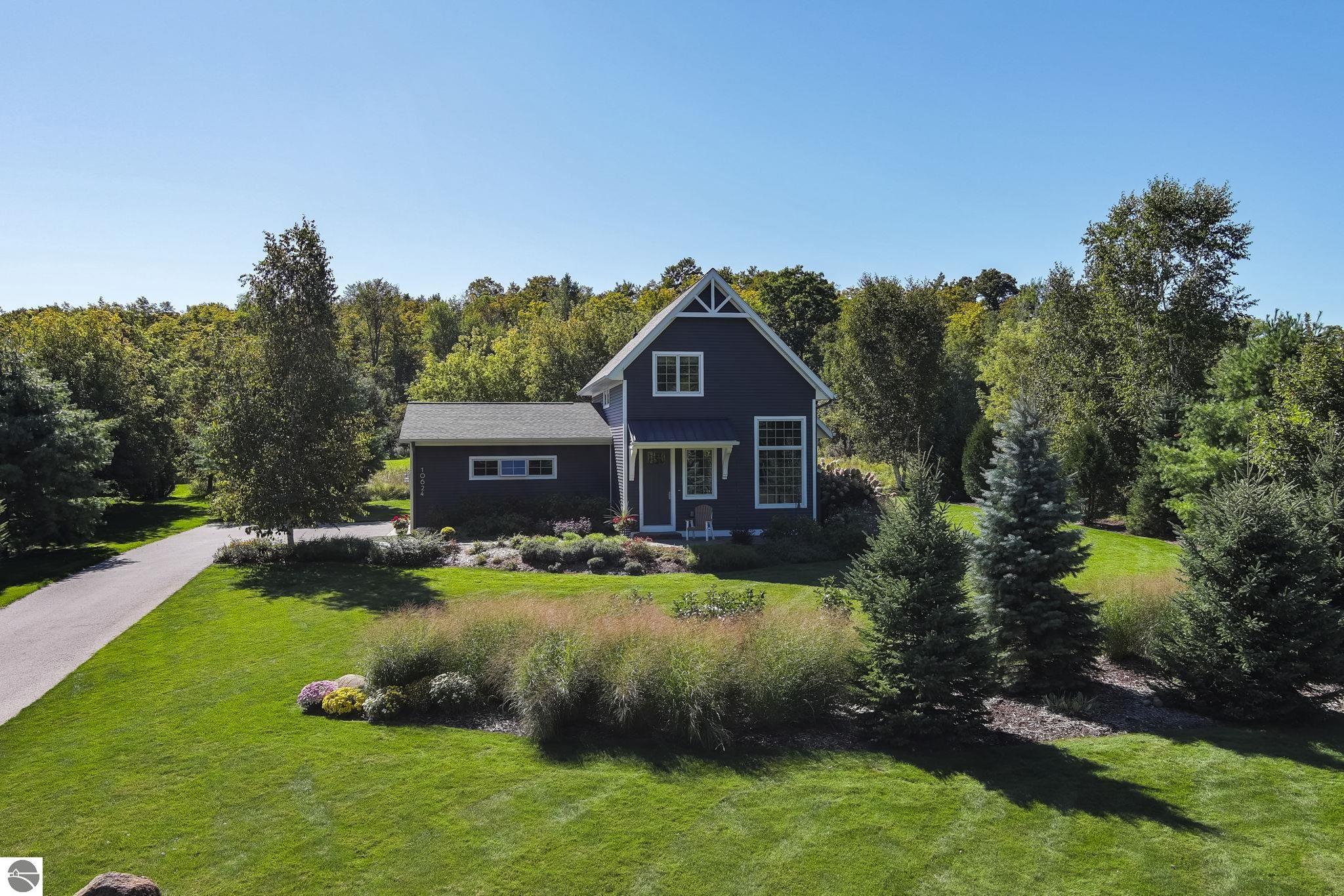 Dark blue two-story house with a steep gable, attached garage, and landscaped lawn.