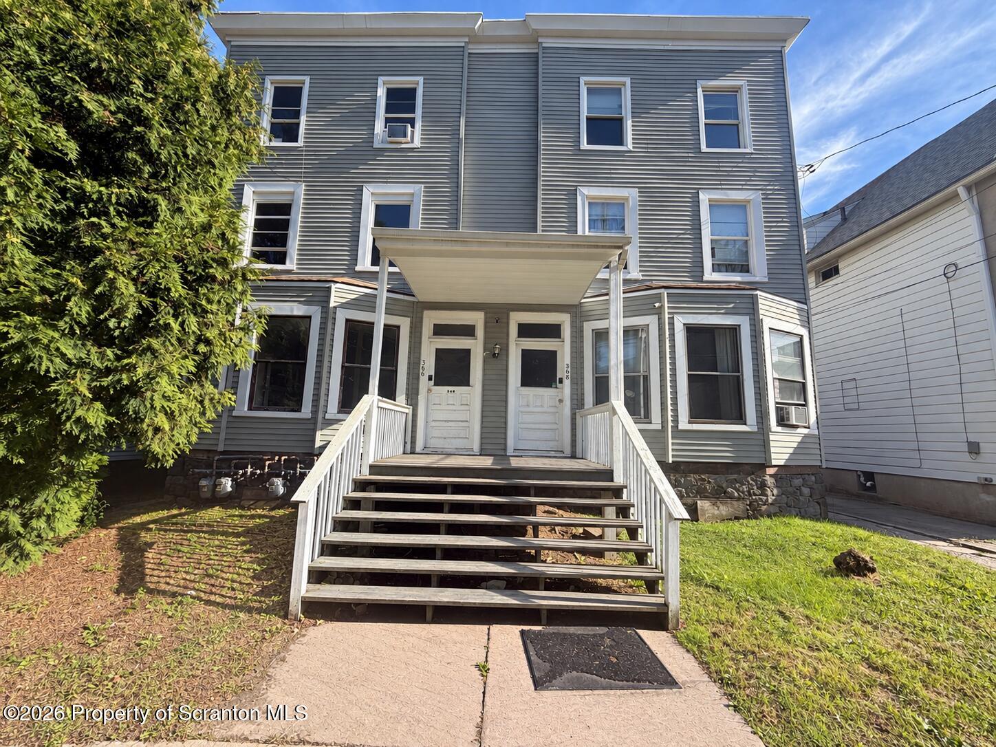 Gray three-story home with two entrances and a wide front staircase.