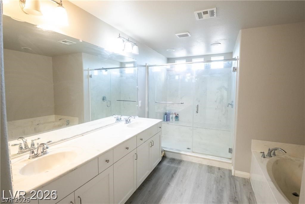 Bathroom with a long double-sink vanity, glass-enclosed shower, and bathtub.