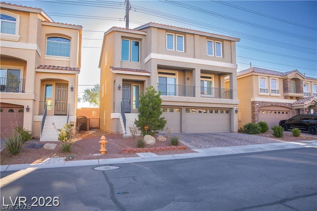Two-story stucco house with a second-floor balcony, two-car garage, and desert landscaping.