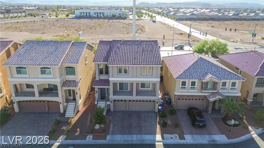 Two-story house with a tiled roof and double garage, seen from above among neighboring homes.