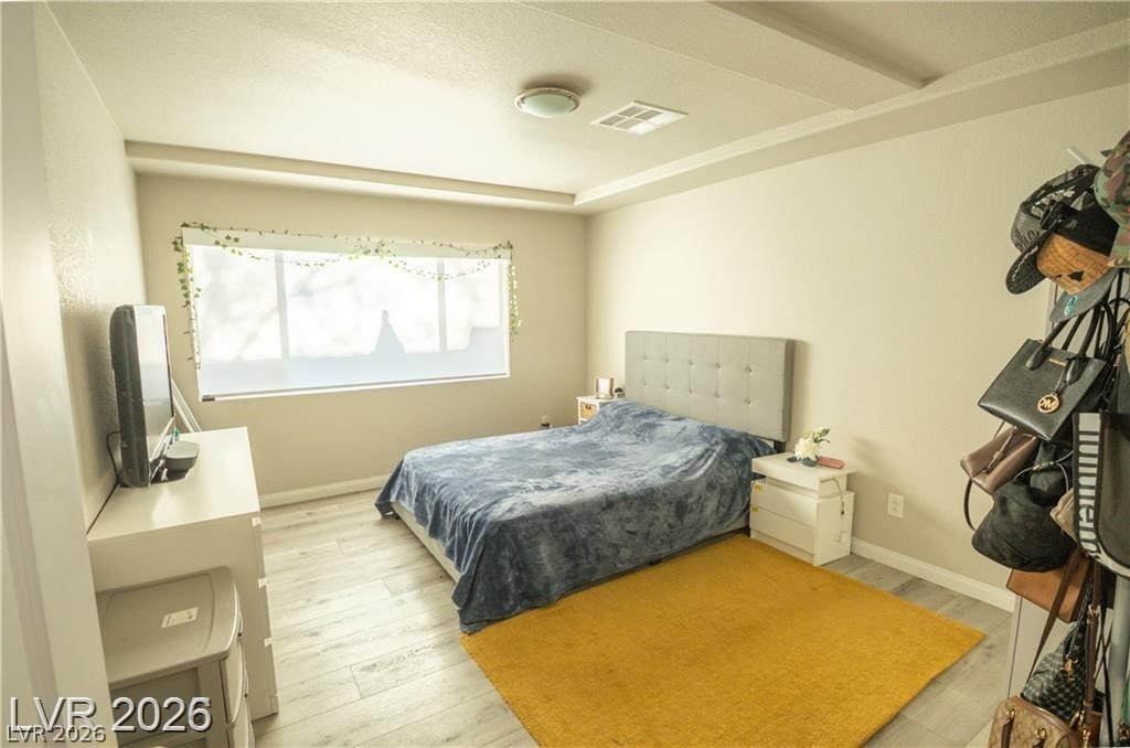 Bedroom with a gray upholstered bed, blue-gray bedding, and a mustard-yellow rug.