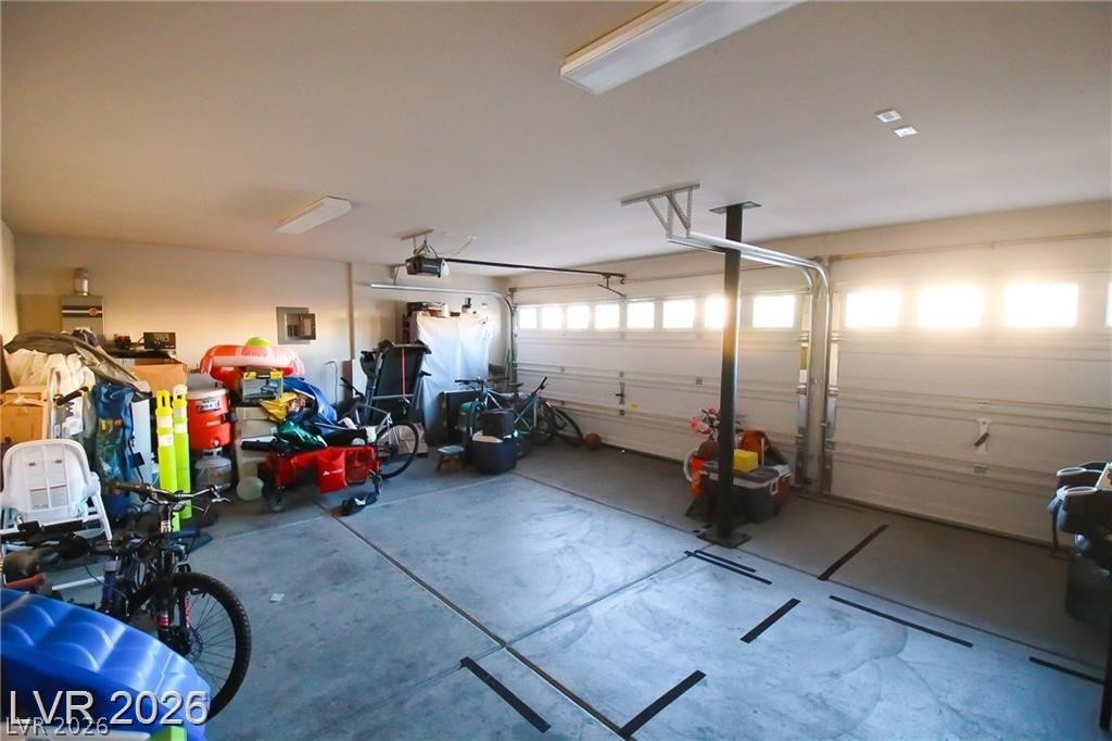 Spacious garage with two doors, open concrete floor, and bicycles and storage along one side.