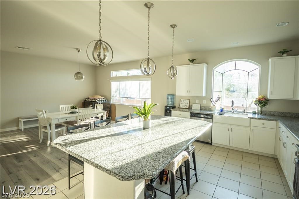 Kitchen with a large granite island, white cabinetry, and an arched window above the sink.