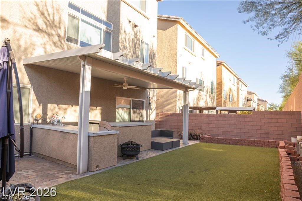 Backyard with a covered patio, outdoor kitchen, lounge seating, and artificial turf.