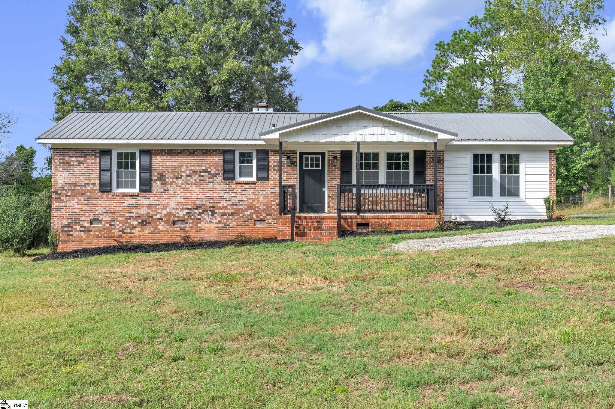 Single-story brick ranch house with a gray metal roof and covered front porch.