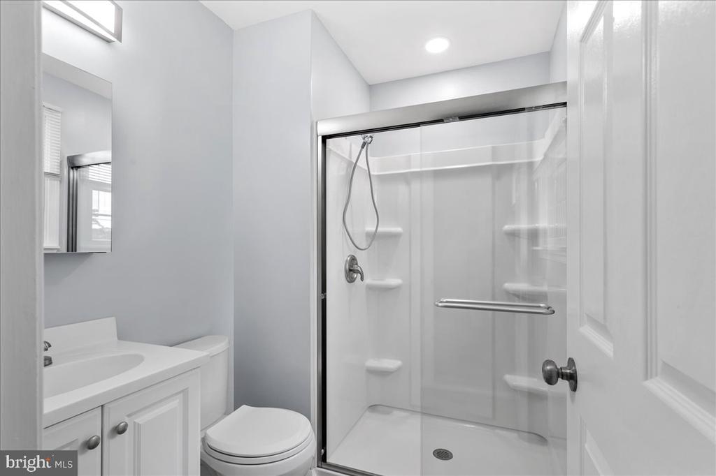 Bathroom with a white vanity, toilet, and glass-enclosed shower with built-in shelves.