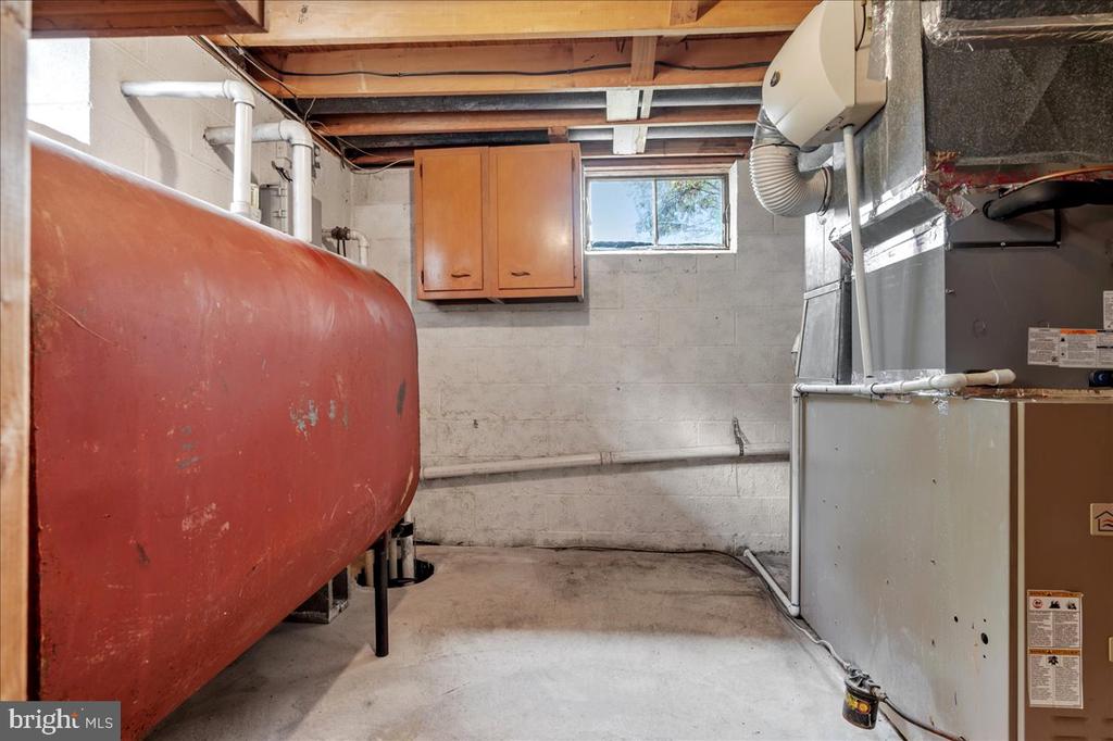 Basement utility room with a large red oil tank and heating equipment.