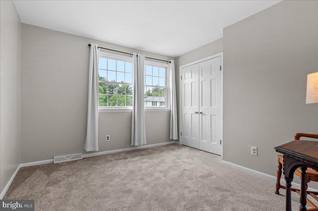 Mostly empty carpeted bedroom with two curtained windows and a white double-door closet.