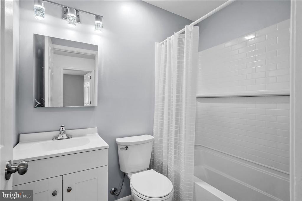 Bathroom with a white vanity, mirrored cabinet, and tub-shower with subway tile.