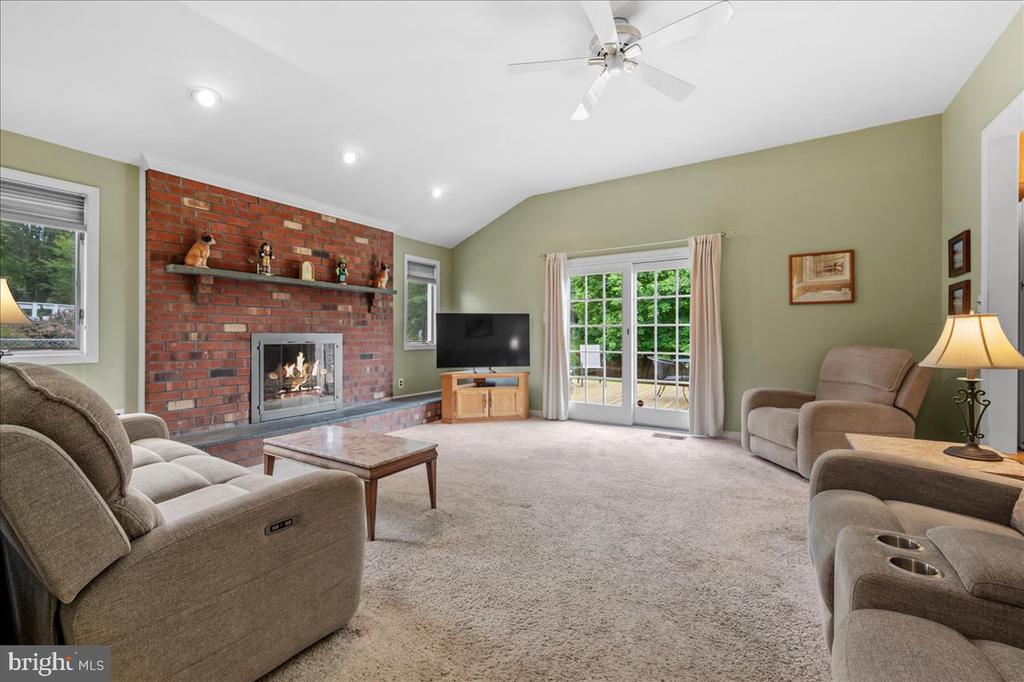 Living room with a brick fireplace, beige seating, and glass doors to a patio.
