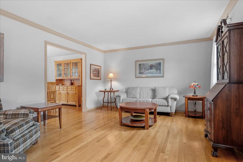 Living room with hardwood floors, a white sofa, and a large dark wooden display cabinet.