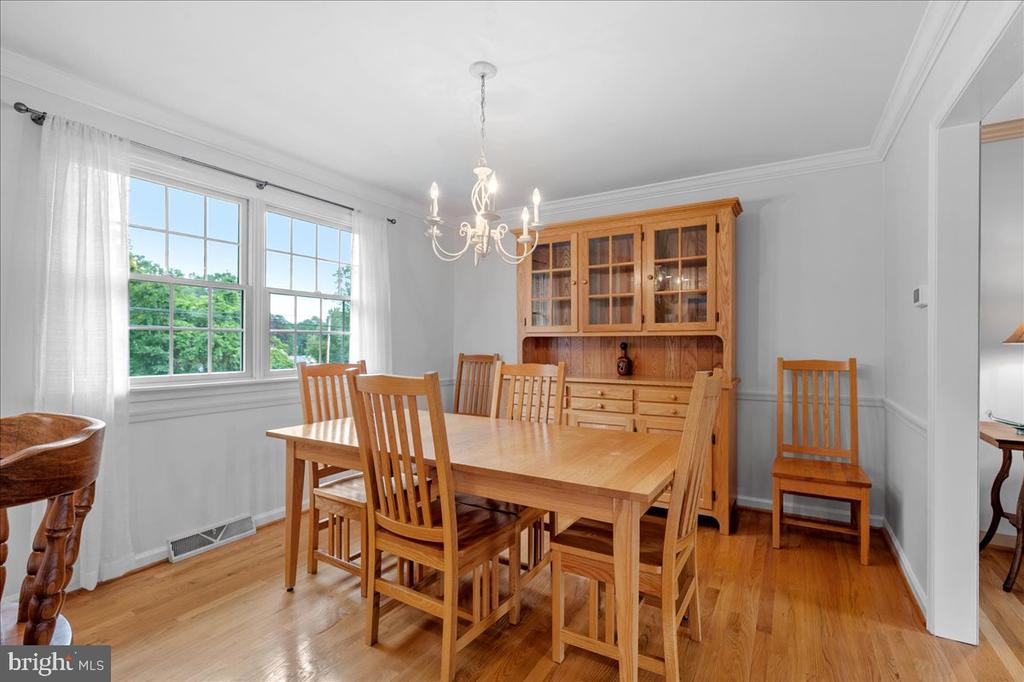 Dining room with a wooden table and china cabinet beside tall windows.