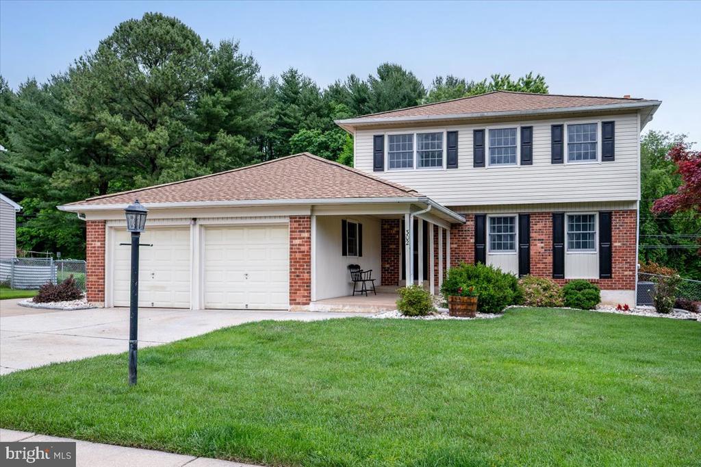 Two-story brick-and-siding house with black shutters, a two-car garage, and a covered entry.