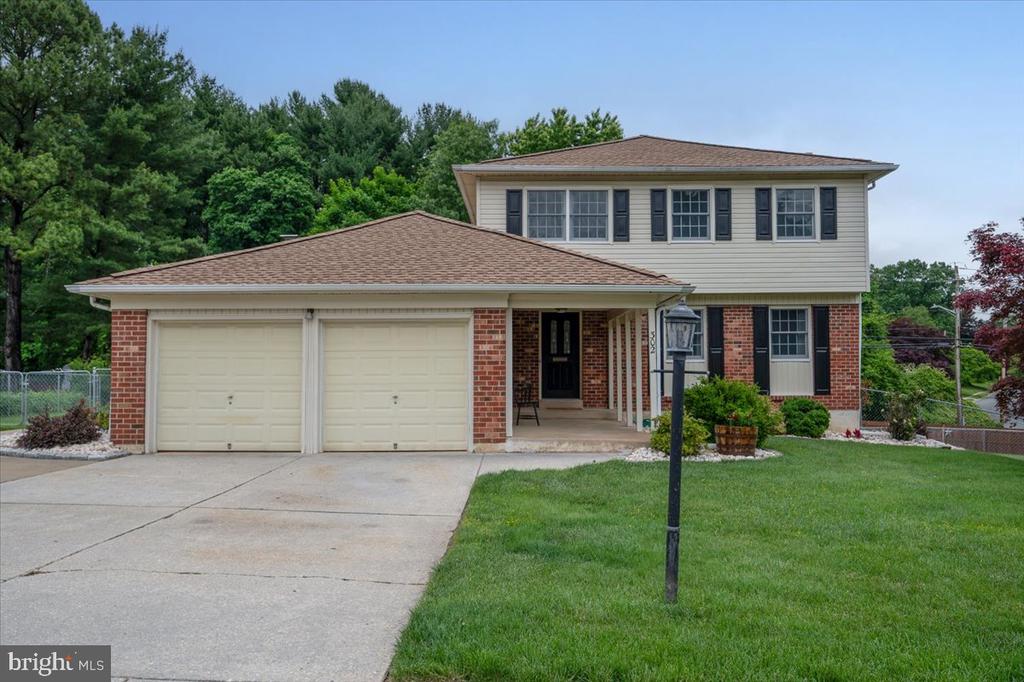 Two-story brick and siding home with a two-car garage, wide driveway, and green lawn.