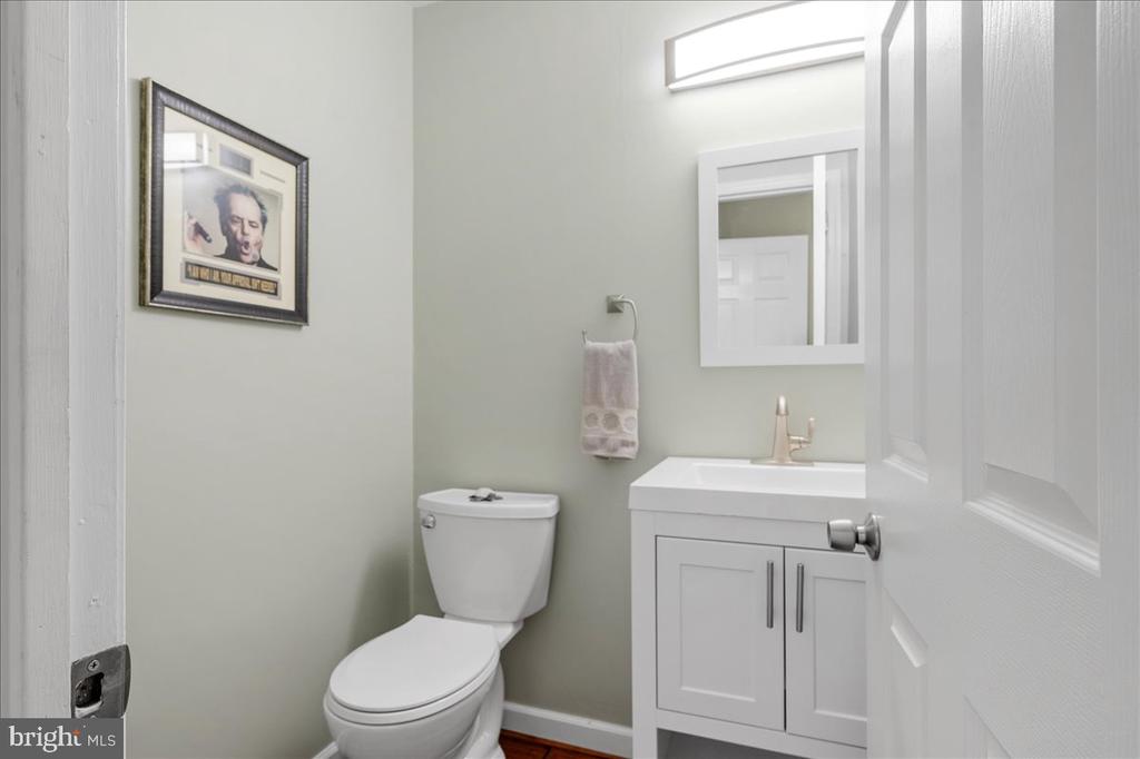 Bathroom with a white toilet and vanity, rectangular mirror, and framed wall art.