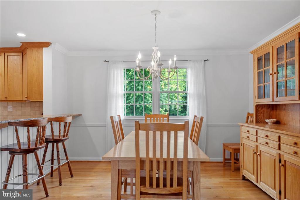 Dining room with a wooden table, chandelier, large garden-facing windows, and built-in wooden cabinetry.