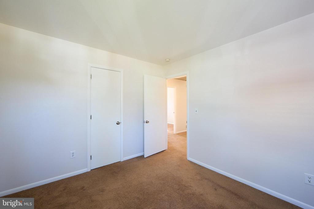 Empty carpeted room with white walls, a closed door, and an open doorway.