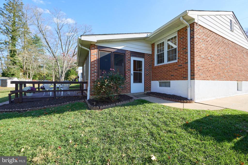 Brick home with a screened entry, raised deck, and broad front lawn.