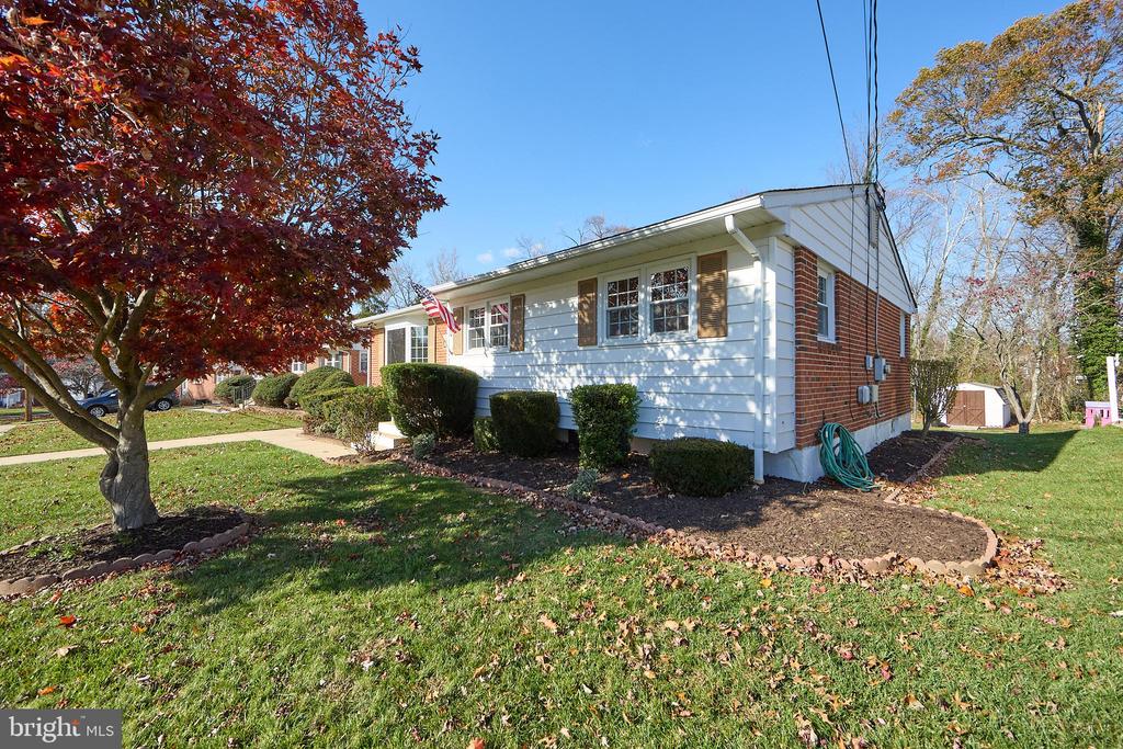 Single-story home with white siding, brick accents, and a landscaped front yard in autumn.