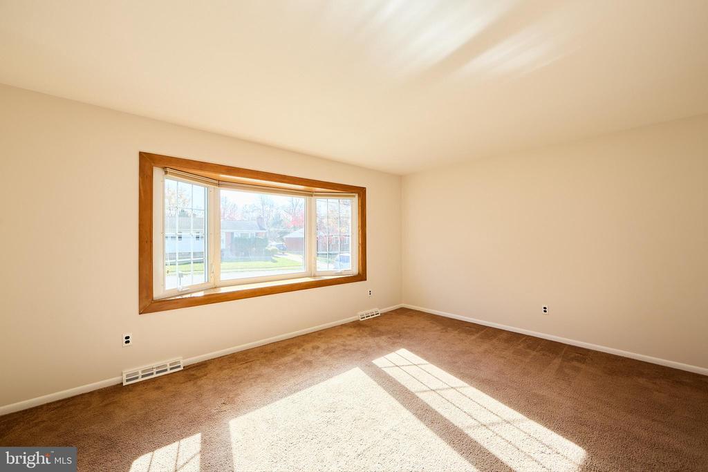 Vacant bedroom with brown carpet and a large wood-trimmed window.