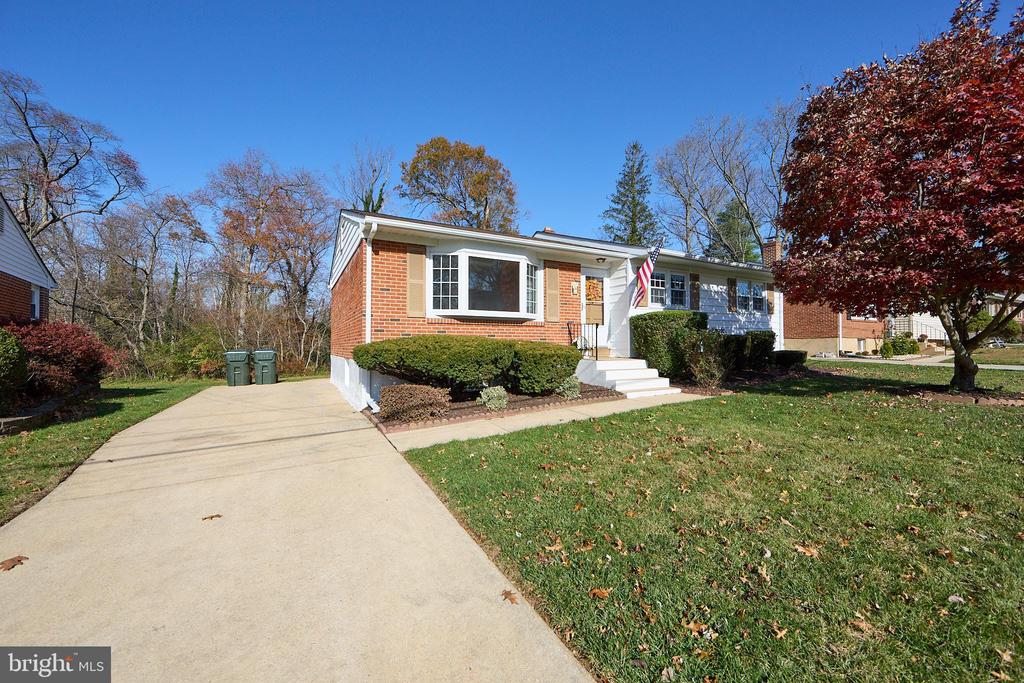 Brick-and-siding split-level home with a wide driveway, front steps, and mature autumn trees.