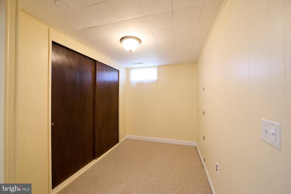 Empty carpeted room with dark sliding closet doors and a small high window.