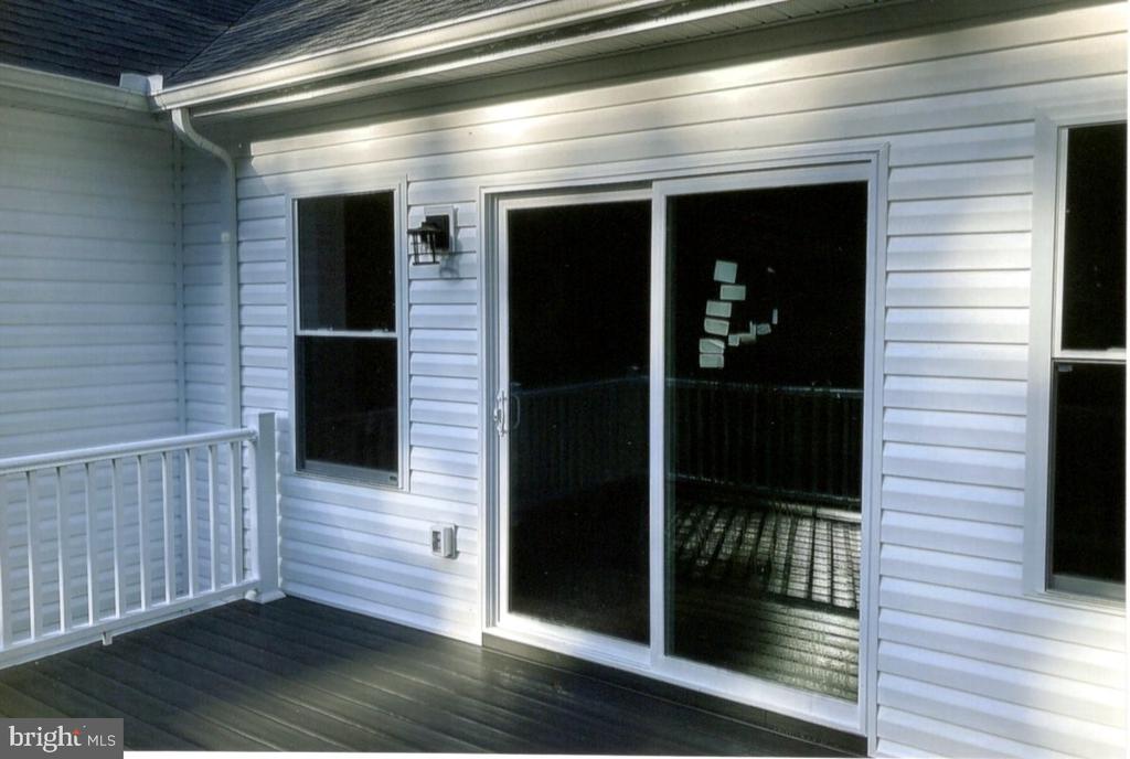 Covered deck with dark floorboards, white railing, and a sliding glass door.