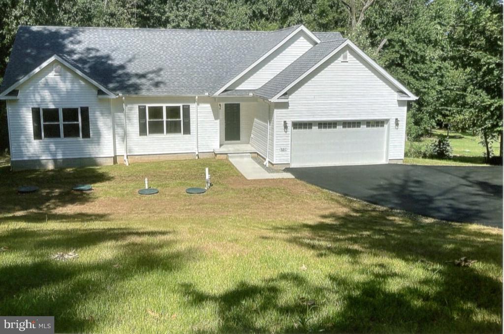 White single-story house with a two-car garage, lawn, and mature trees.