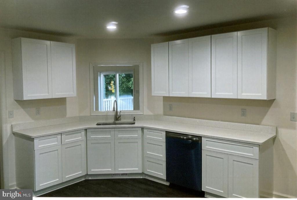 Kitchen with white cabinets, light countertops, a window over the sink, and a black dishwasher.