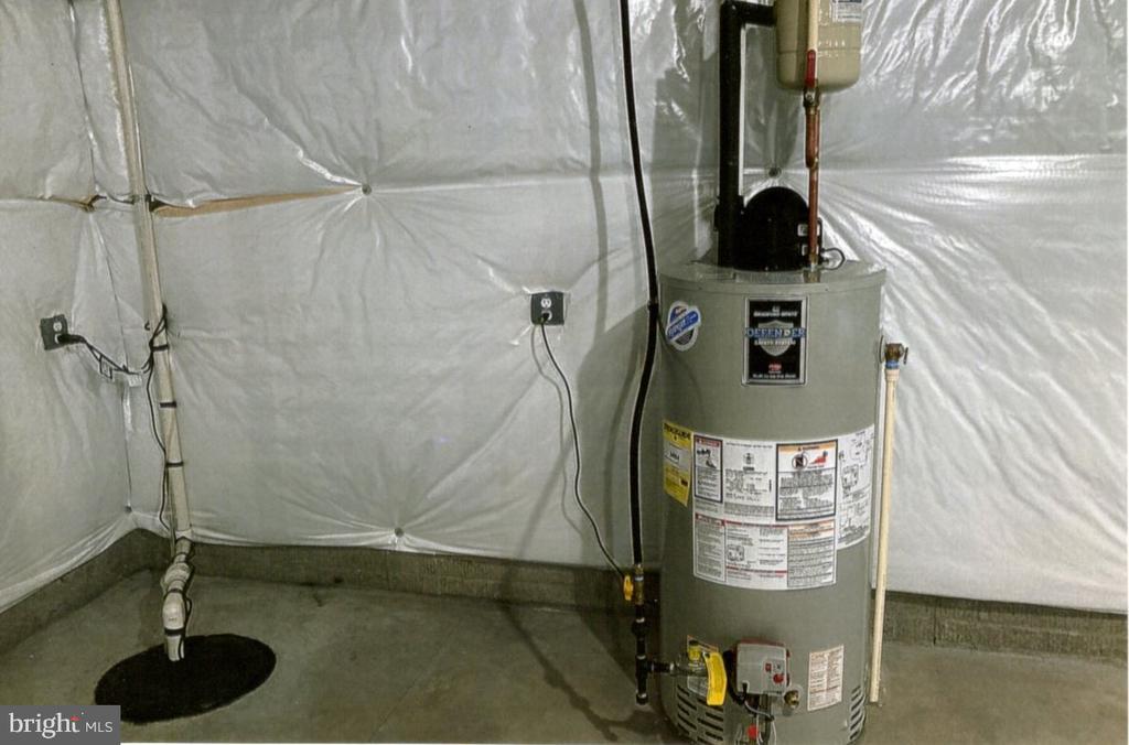 Basement utility area with water heater, insulated walls, and sump pit.