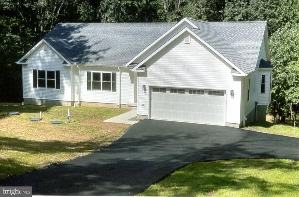 White single-story house with an attached two-car garage and wide asphalt driveway.
