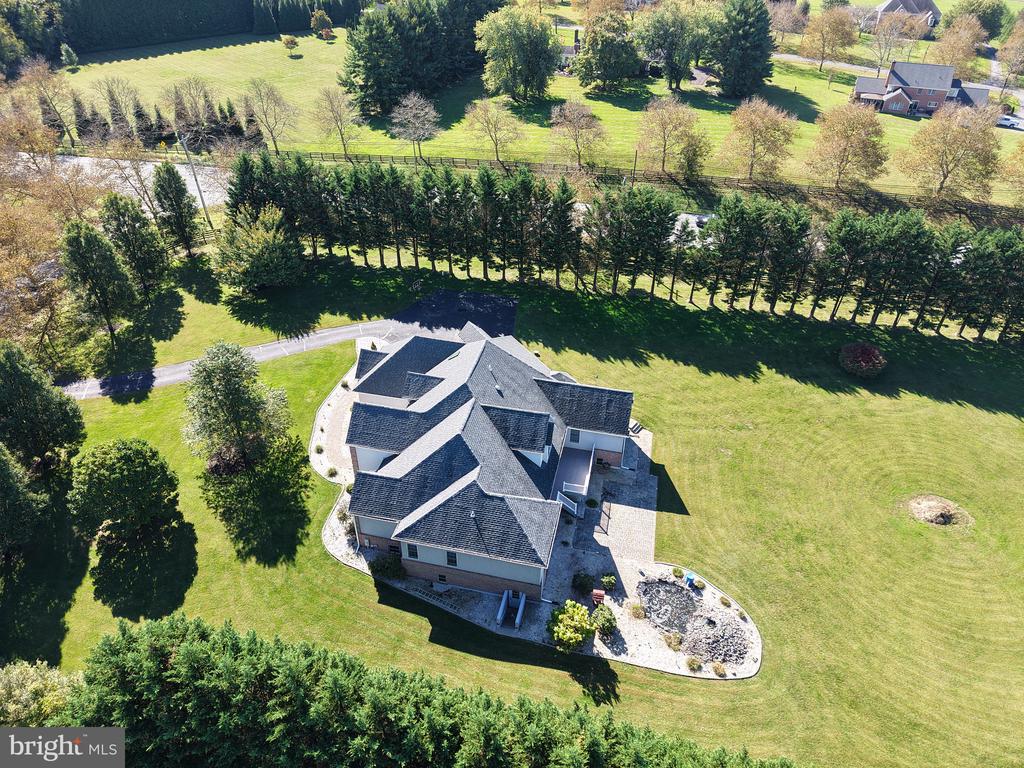 Aerial view of a large home surrounded by expansive lawn and mature trees.