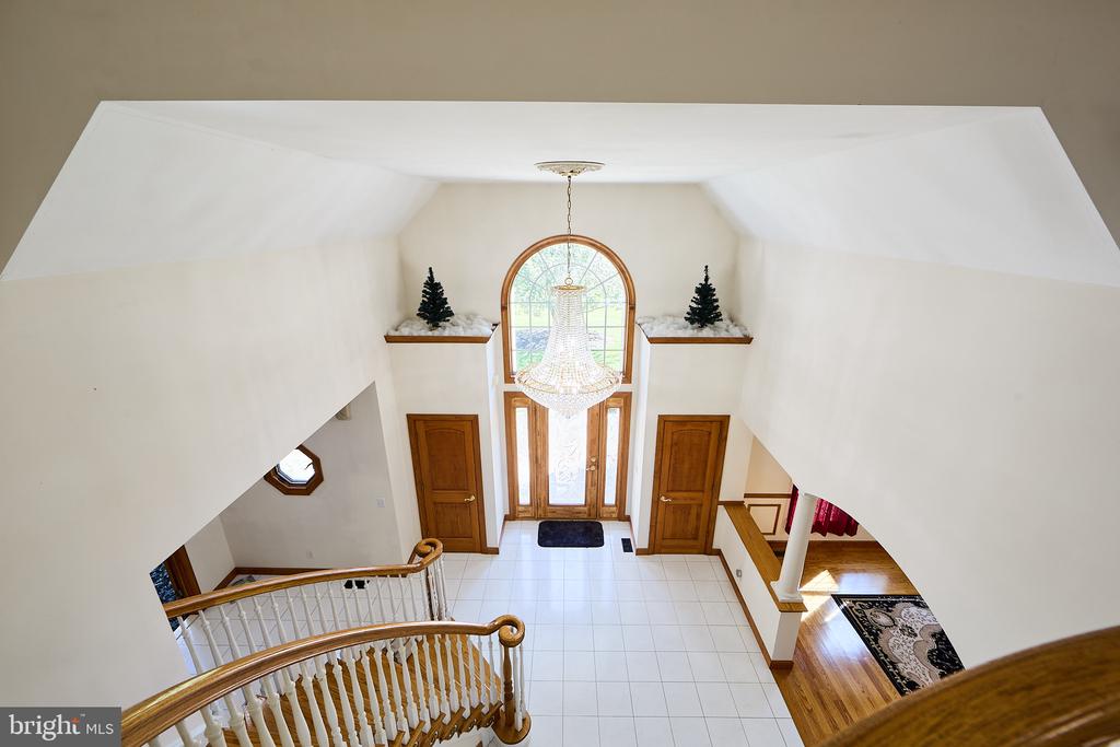 Two-story foyer with a crystal chandelier, tall arched window, and curved staircase railing.