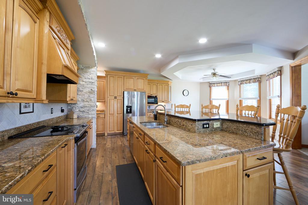 Kitchen with granite island, honey-colored cabinetry, stainless steel appliances and an adjoining dining area.