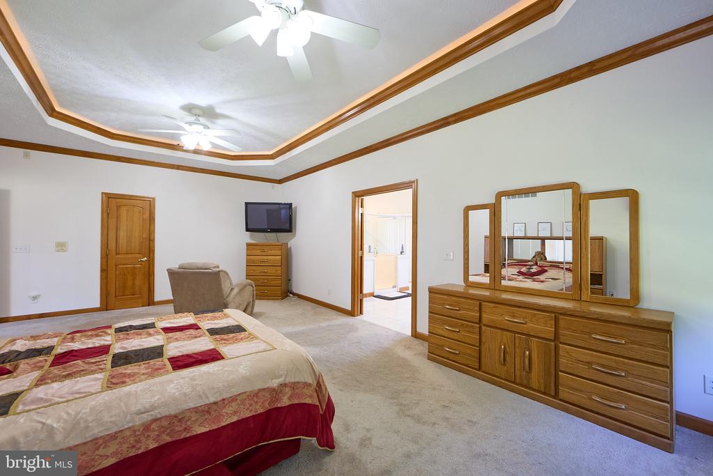 Bedroom with a patterned bedspread, matching wood furniture, and a wood-trimmed tray ceiling.